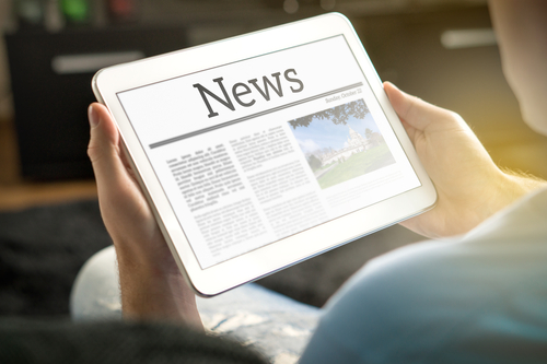Picture of a man holding a smart tablet that says News on the screen.