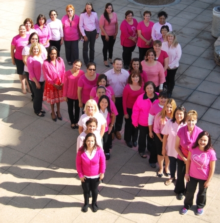 Picture of a The Breast Center Staff standing outside in a form of a Breast Cancer Awareness ribbon. They are all wearing pink shirts.