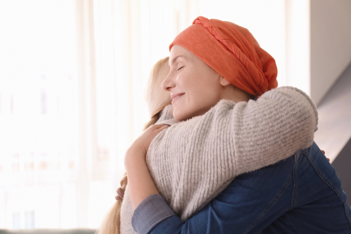 Picture of a female cancer patient smiling as she hugs another female.