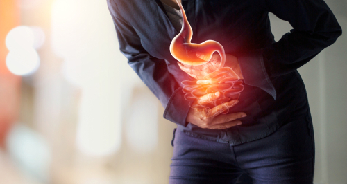 Picture of a man bent slightly over, holding his stomach in pain.