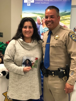Male Officer and female standing next to each other. The Woman is holding a picture of her daughter