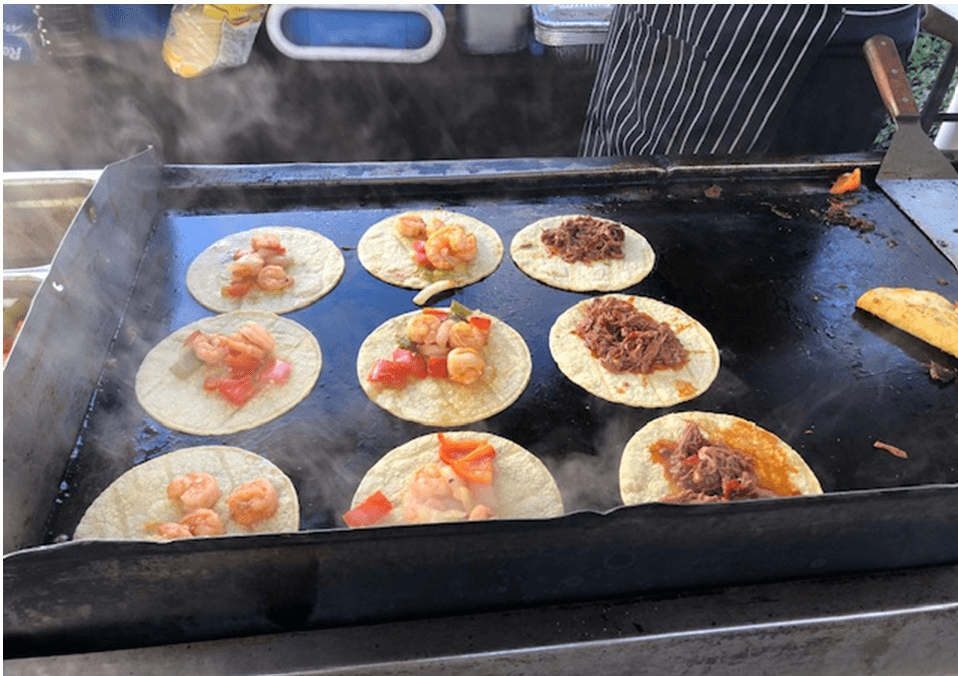 Nine flour tortillas with pork, shrimp, and veggies sitting on a grill outside, during Diana's Family Appreciation Dinner