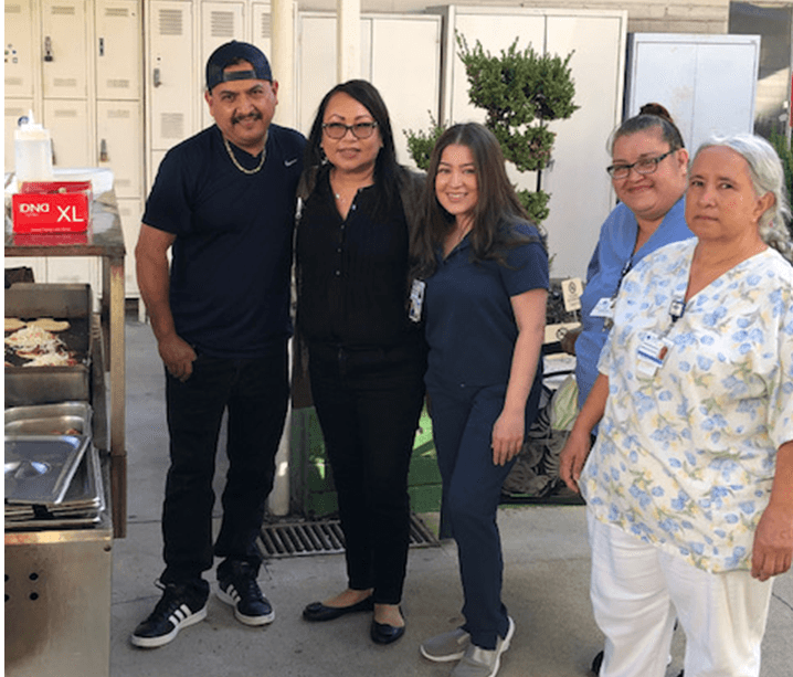 Five smiling Staff (four females and one male) standing outside